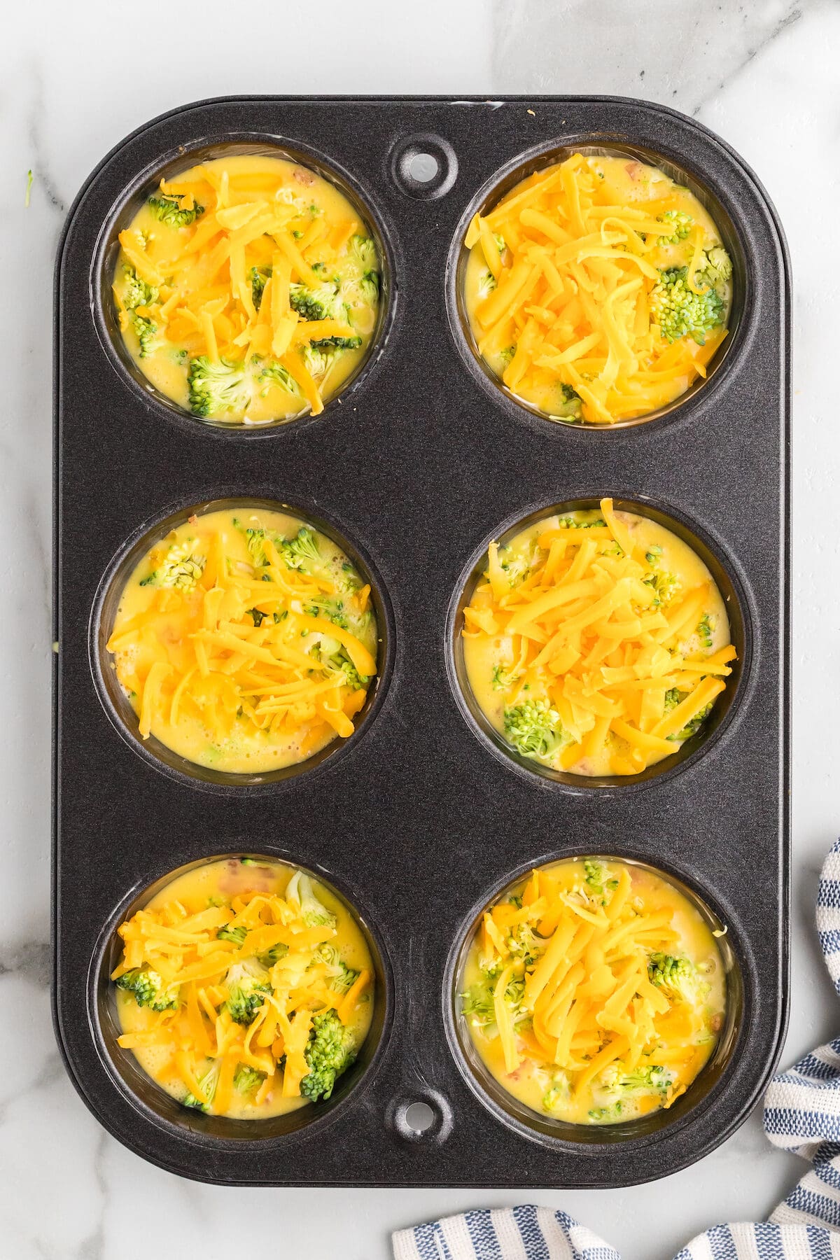 shredded cheddar cheese on the top of the broccoli in the egg muffin cups.