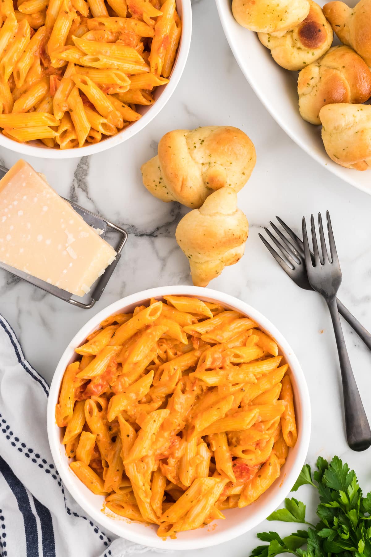 two white bowls filled with pasta and creamy pomodoro sauce. 