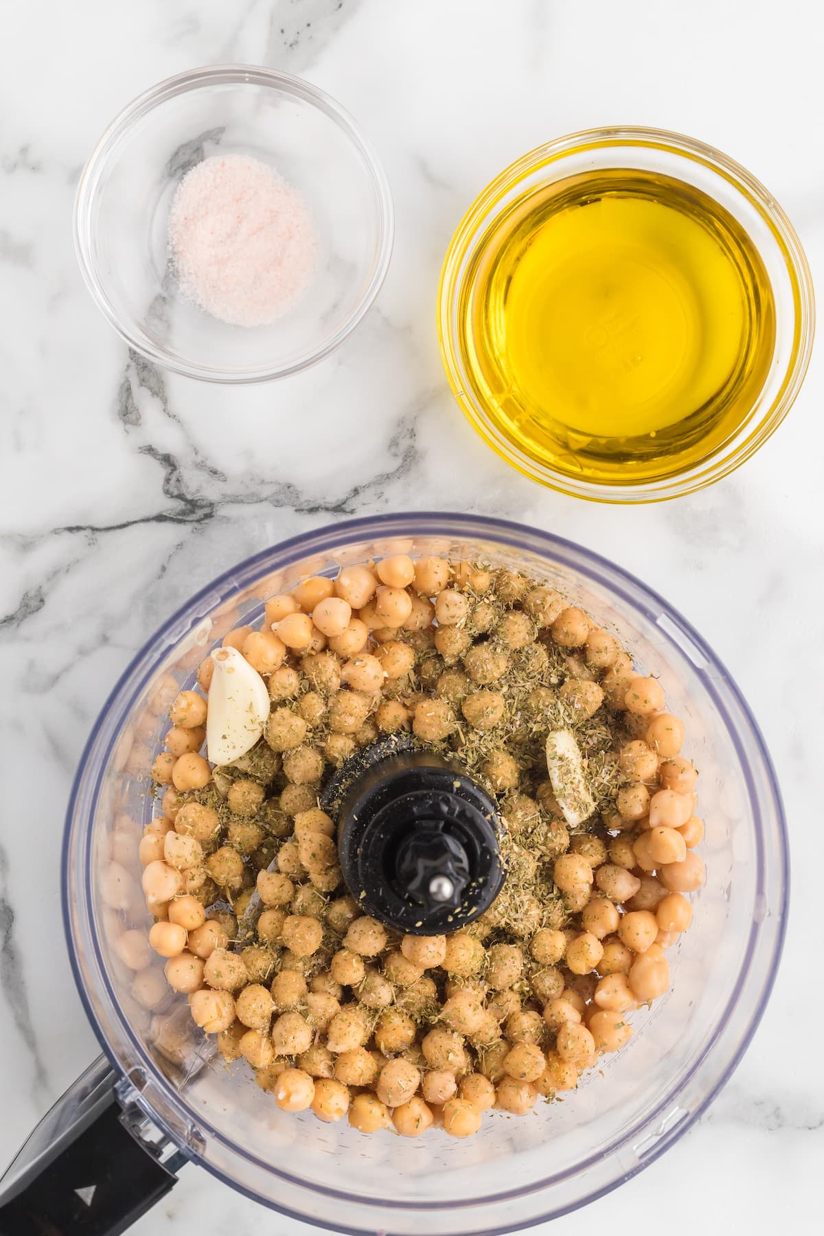 food processor bowl with garbanzo beans, garlic, seasonings. 