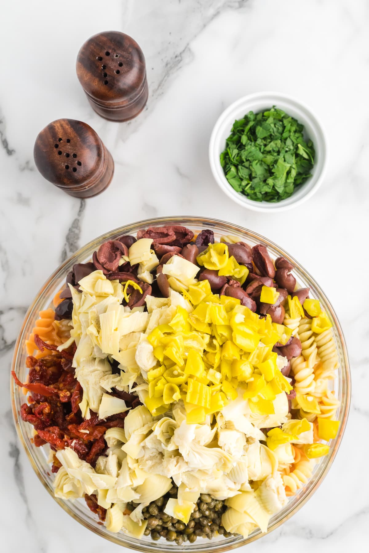 fresh veg in a large bowl with the cooked pasta and herbs to the side.