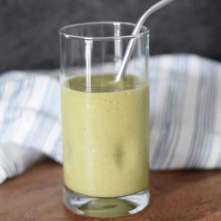 tall glass with green Moringa smoothie and straw.