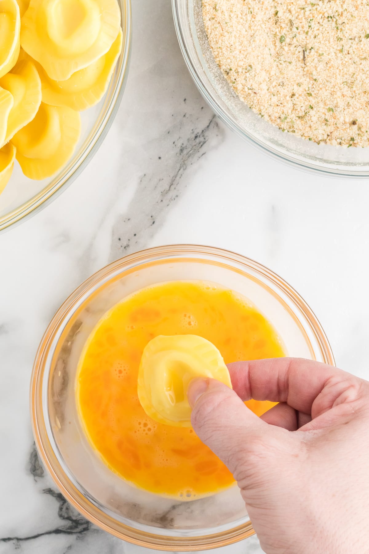 dipping a ravioli in the blended eggs.