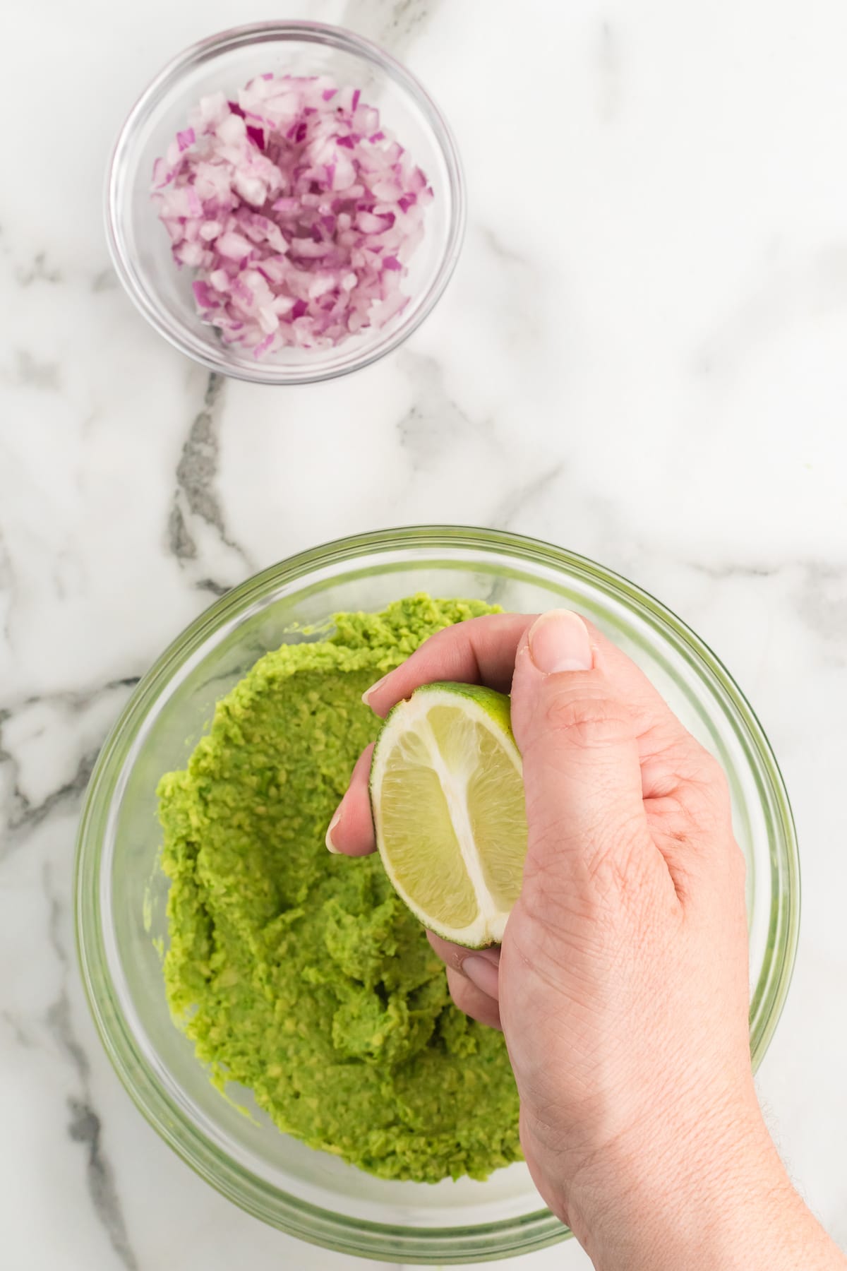 squeezing fresh lime juice over mashed avocado in a large bowl. 