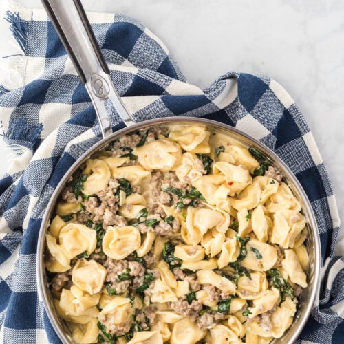 large skillet with creamy tortellini and italian sausage.