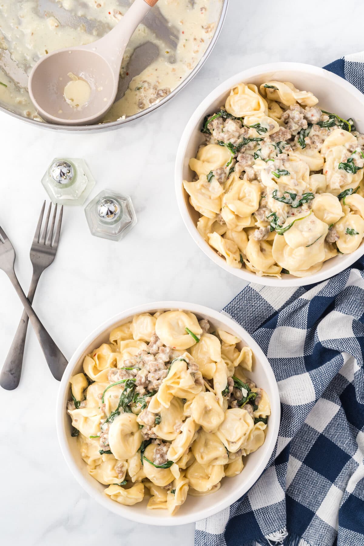 two white bowls filled with creamy tortellini.