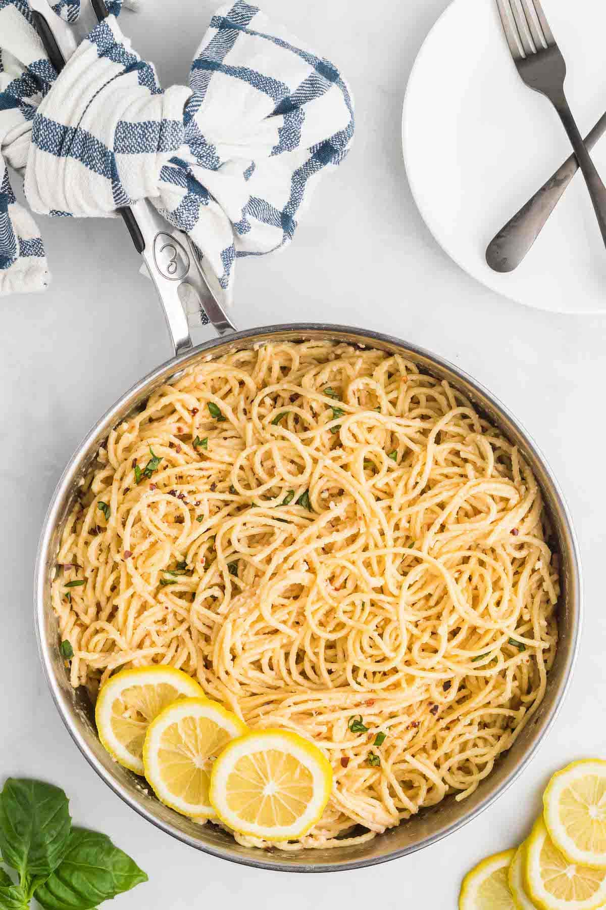 skillet with creamy lemon pasta and lemon slices to the side as garnish.