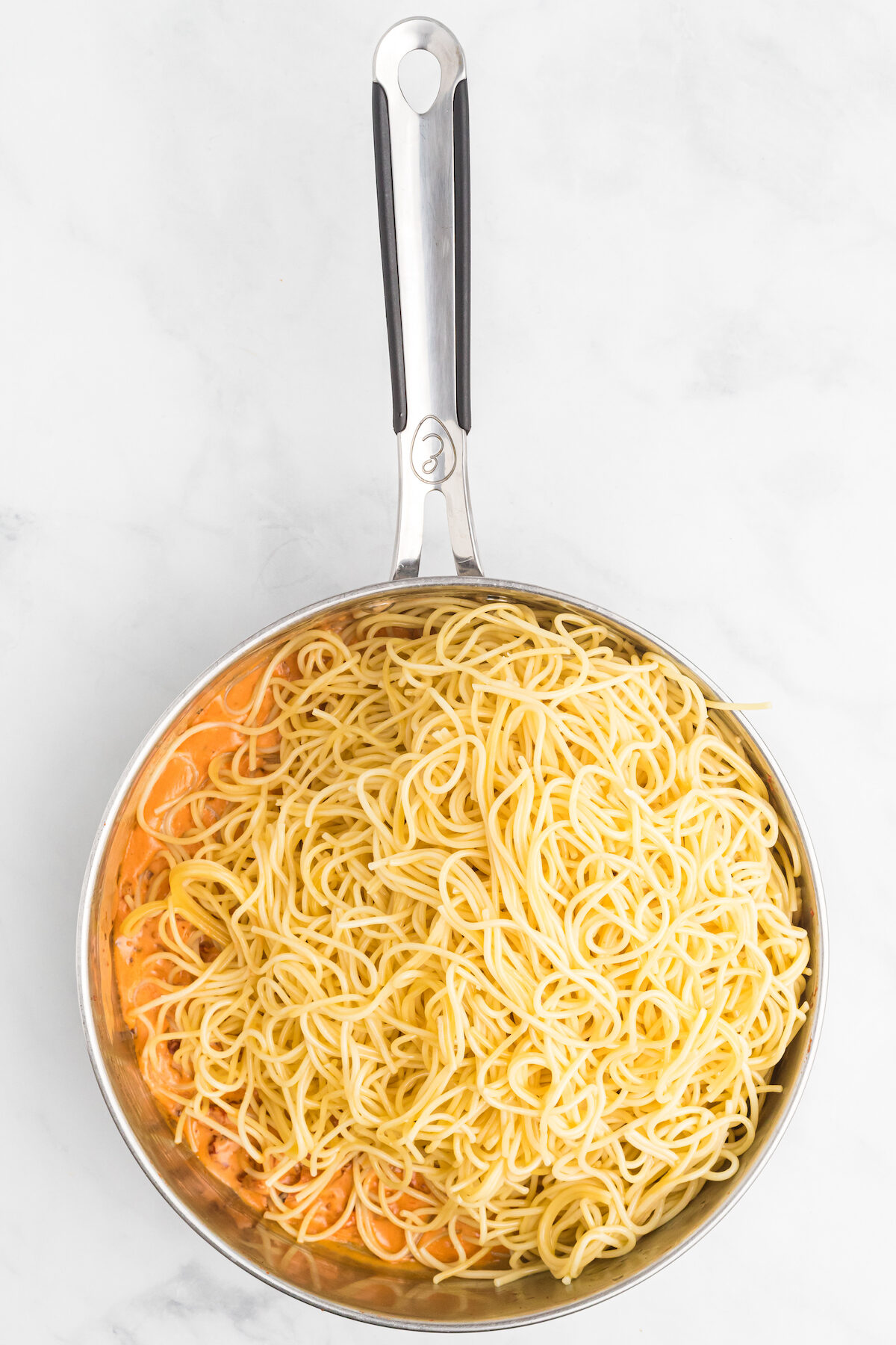 cooked spaghetti noodles added to the sun dried tomato cream sauce in the skillet. 