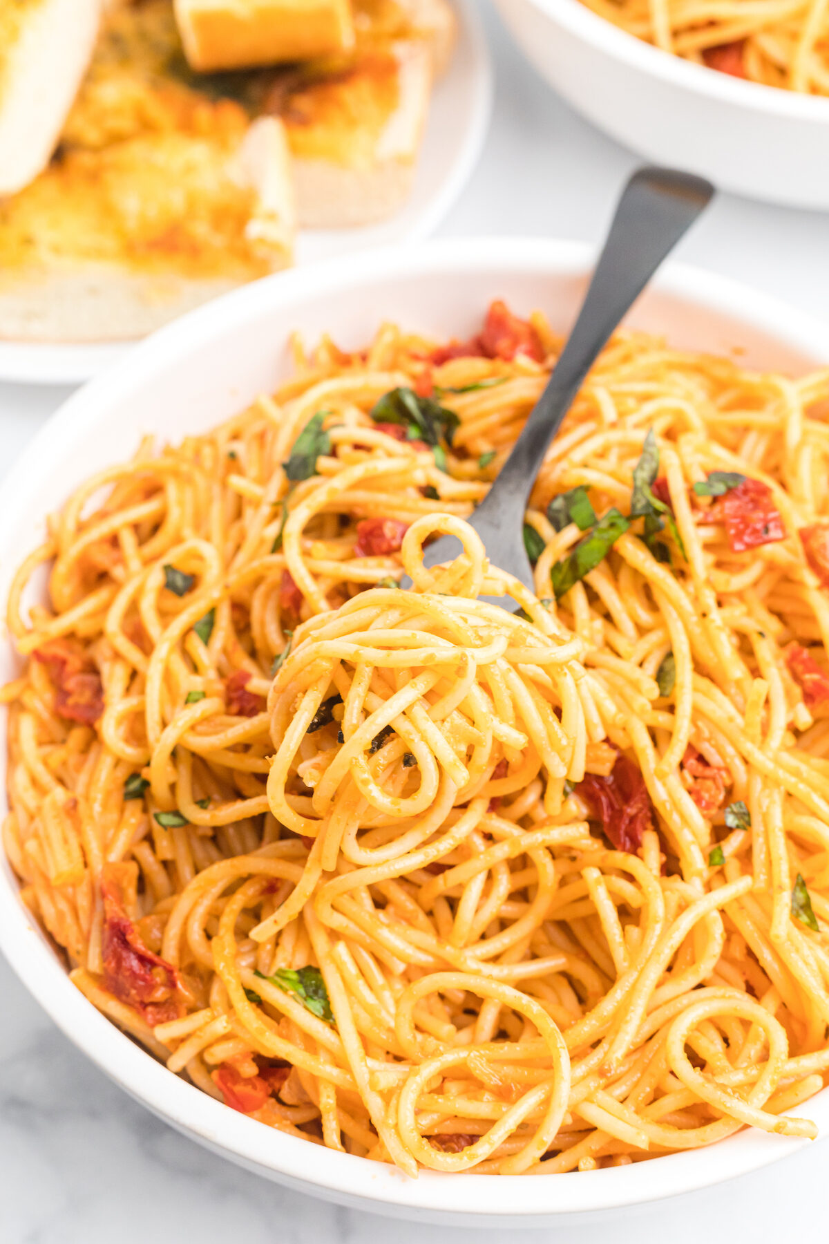 large white pasta bowl filled with creamy pasta with a forkful of spaghetti. 