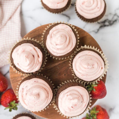 nutella cupcakes topped with strawberry buttercream and stacked over the top of a wooden cake stand.
