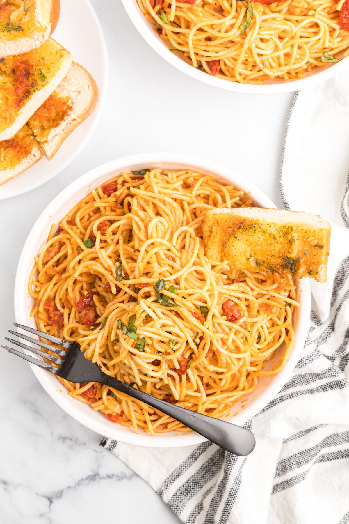 white pasta bowl filled with sun-dried tomato cream sauce pasta. 