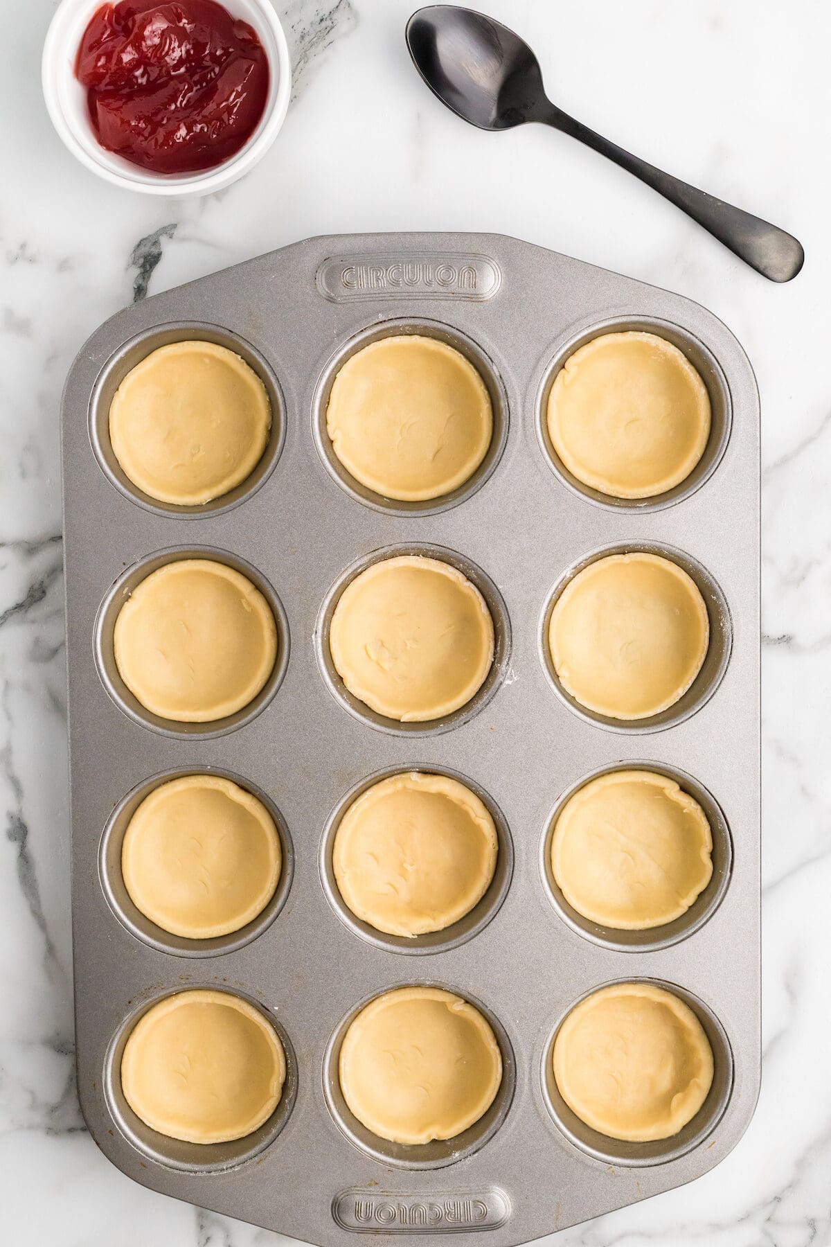jam tart pastry filled inside of a muffin pan.