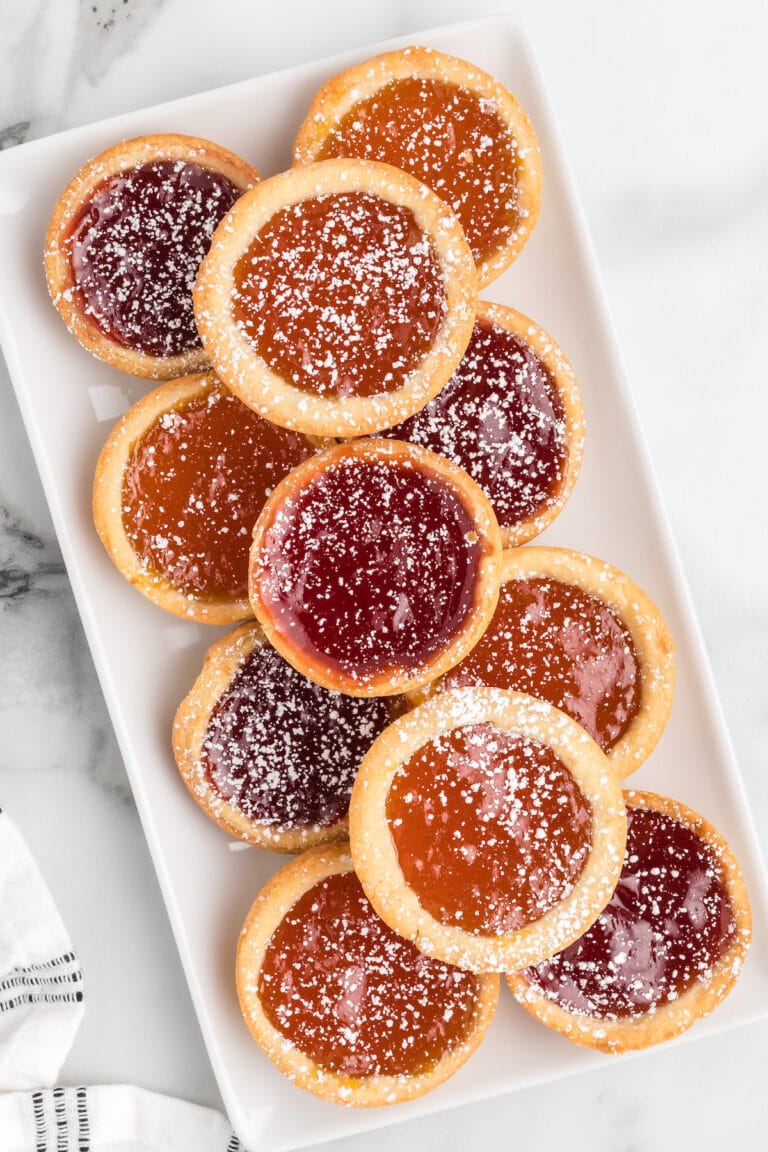 variety of jam tarts on a white platter.