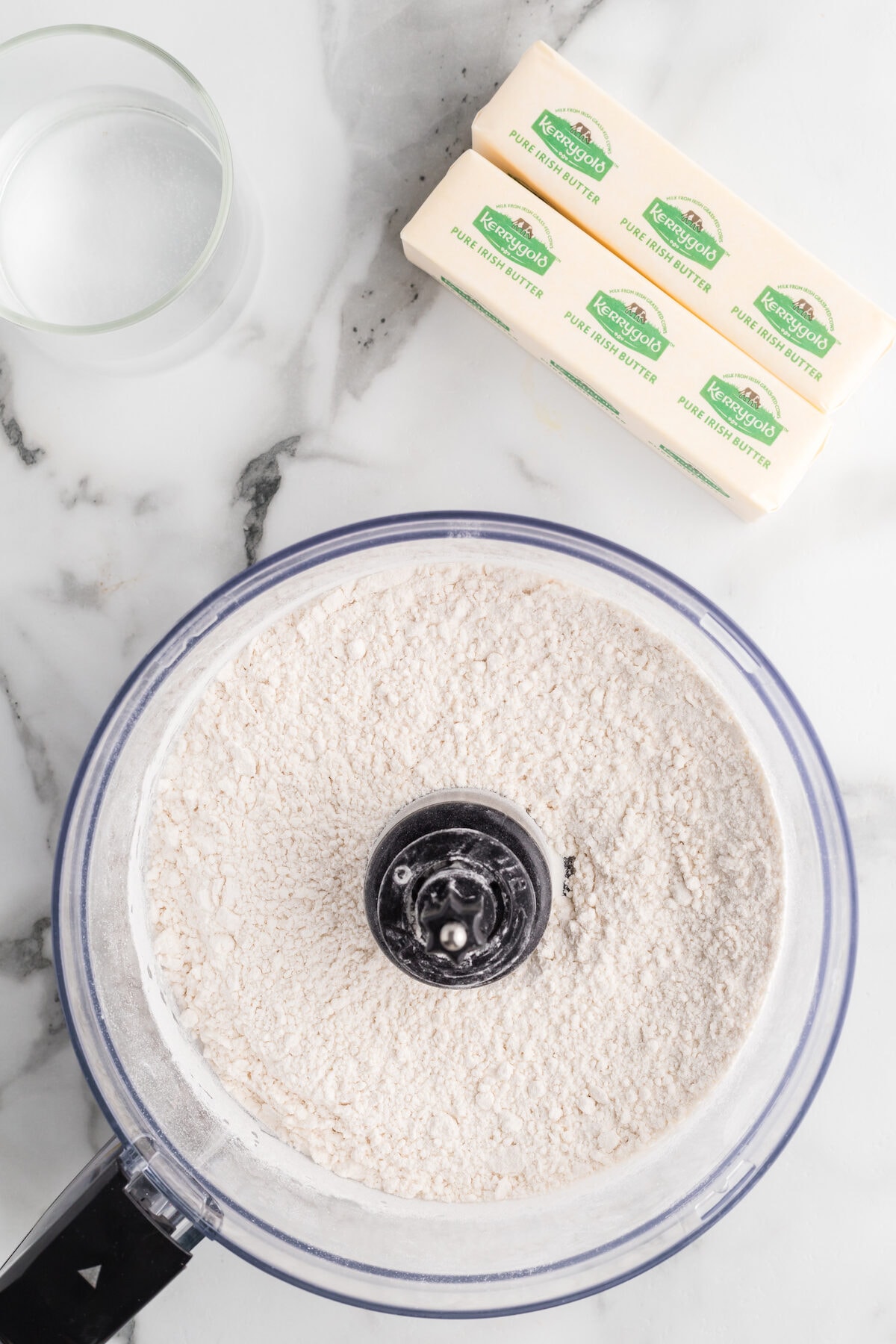 food processor with flour and dry ingredients. The sticks of butter are to the side.