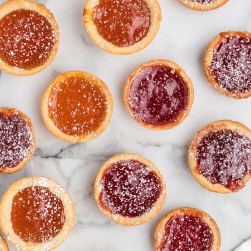 jam tarts lightly dusted with powdered sugar and on a countertop.