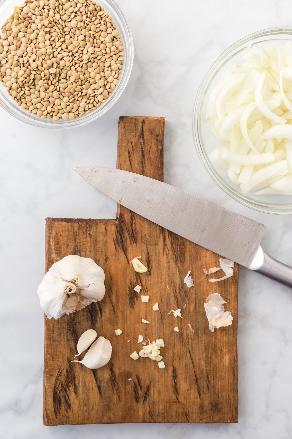 chopping garlic on a small wooden cutting board.