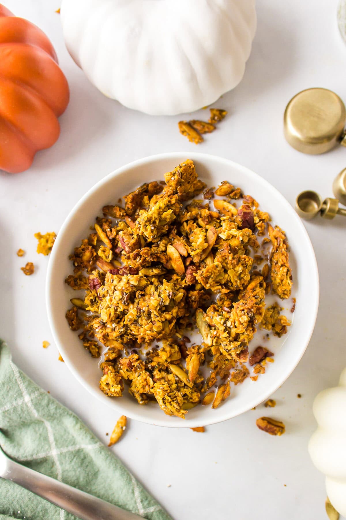 white bowl filled with finished maple pumpkin granola recipe and milk over top.