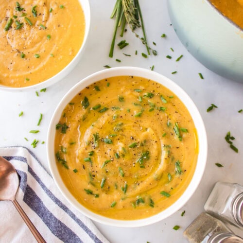 garnishes added to the creamy soup in white soup bowls.