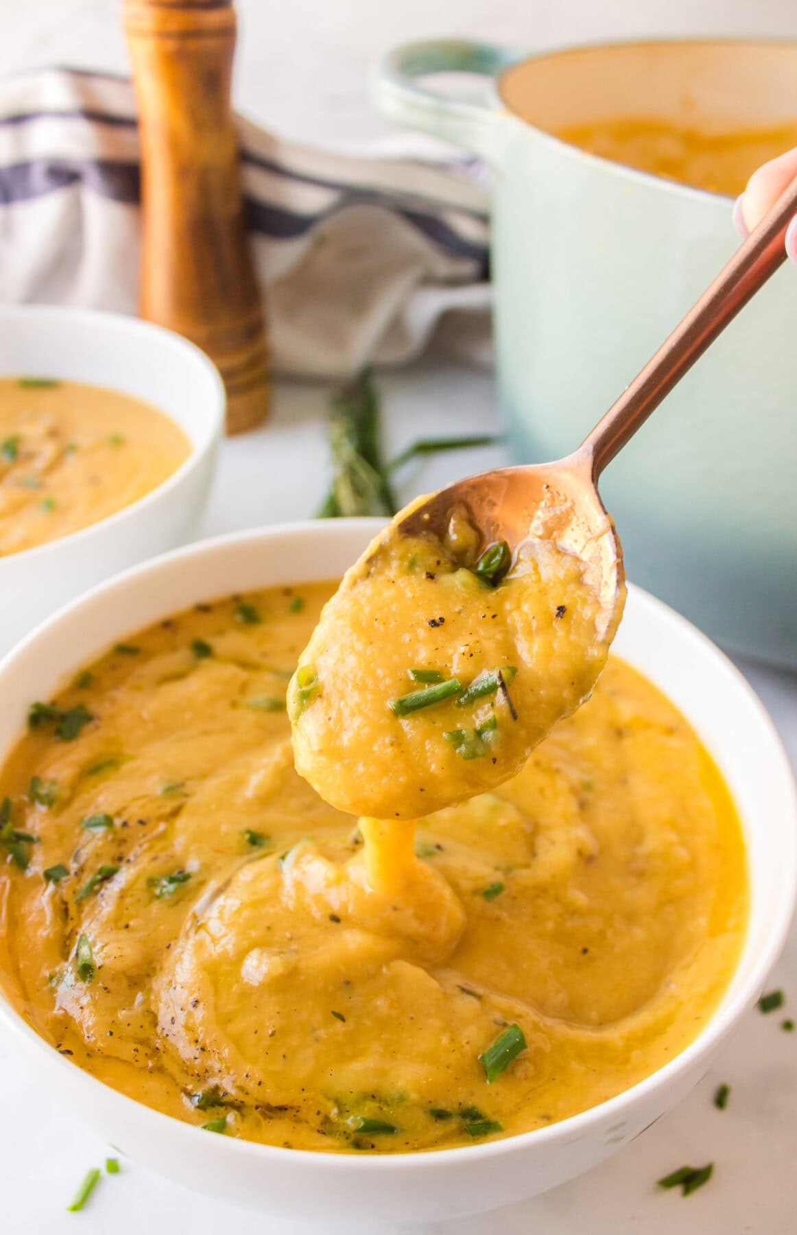 using a spoon inside of the bowl of creamy soup to show the texture.