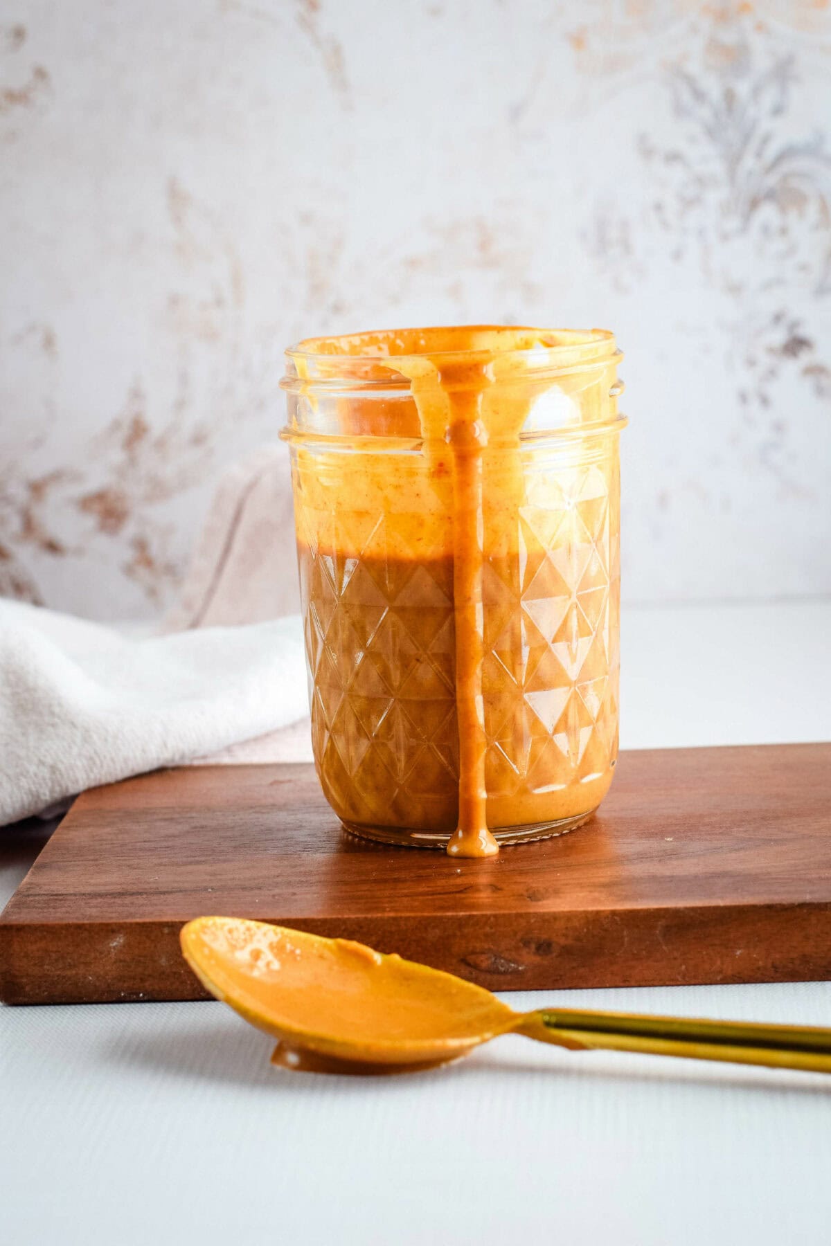 thai peanut sauce in a small mason jar with a spoon resting in front. 