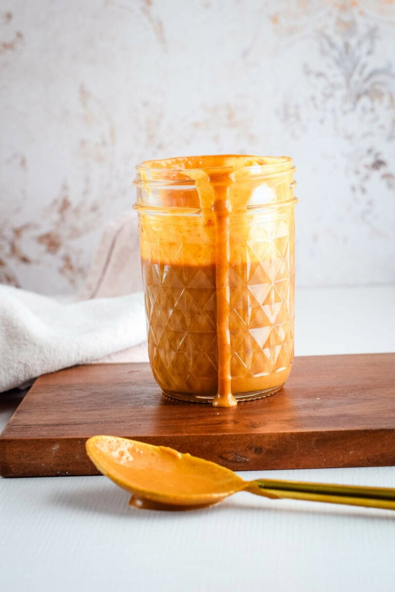 thai peanut sauce in a small mason jar with a spoon resting in front.