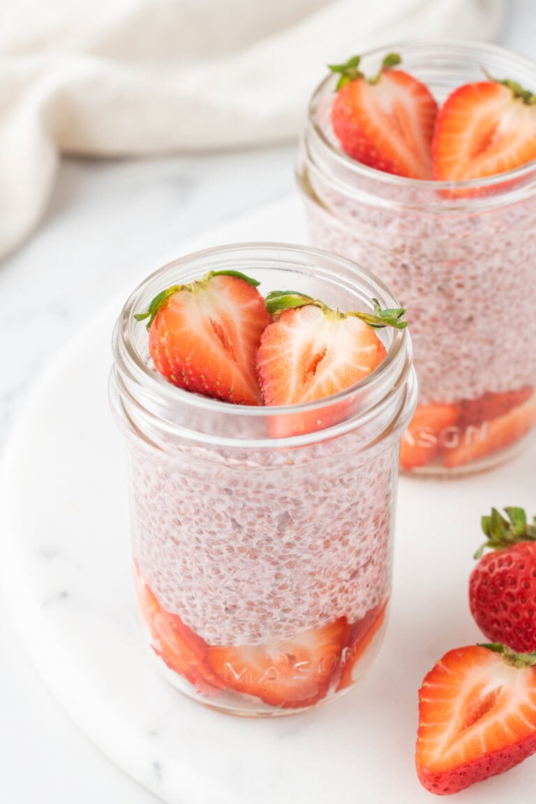 two small mason jars filled with plant based strawberry chia pudding.