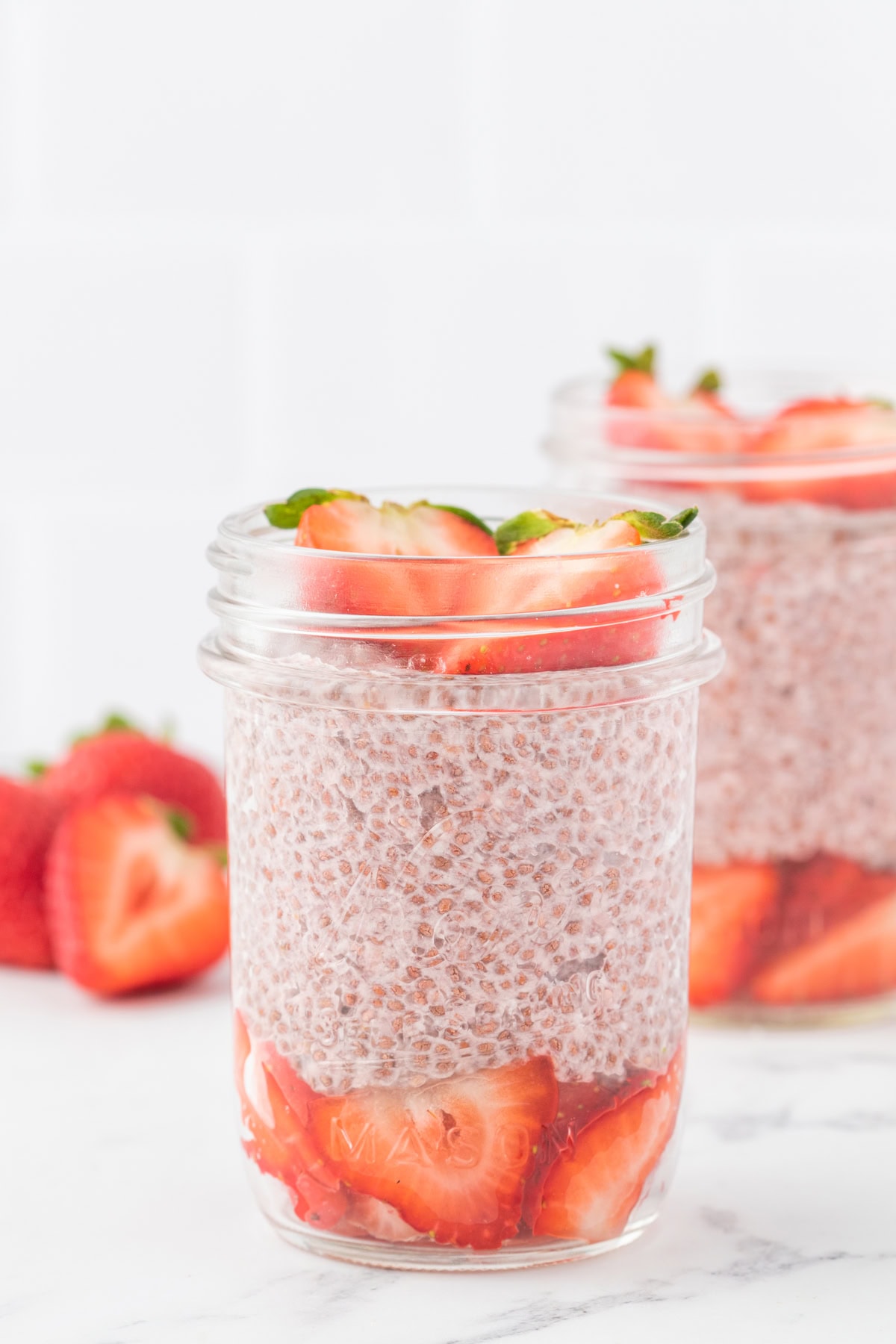 strawberries and plant based chia seed pudding layered in a mason jar like a parfait. 